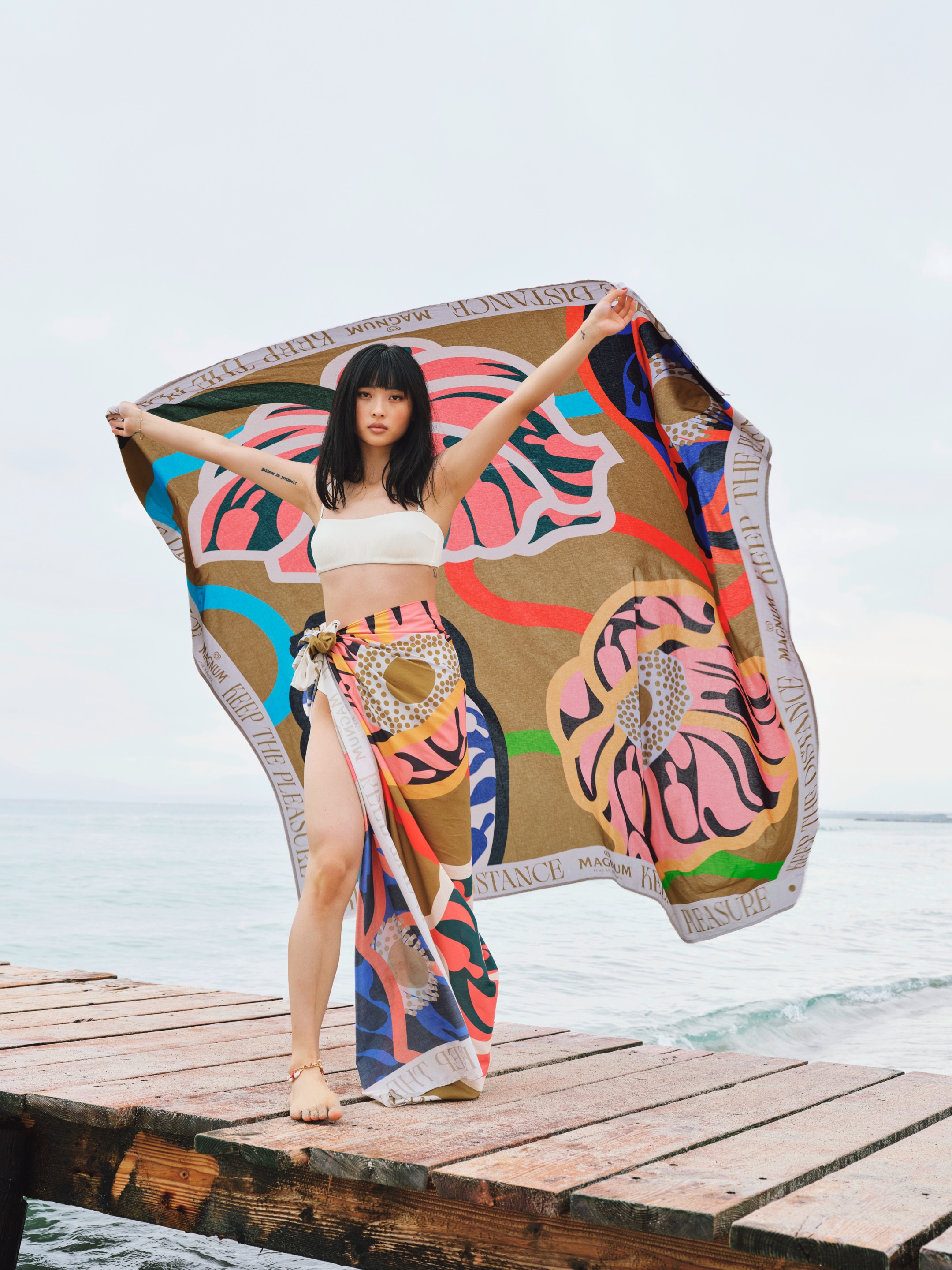 Model wears a magnum designer sarong, with a magnum floating towel behind