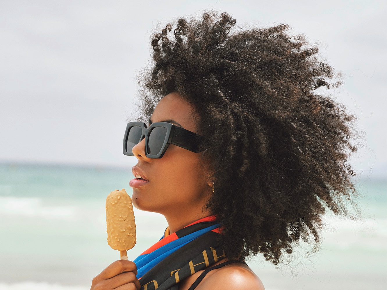 Model holding a magnum ice cream with a Magnum towel floating behind