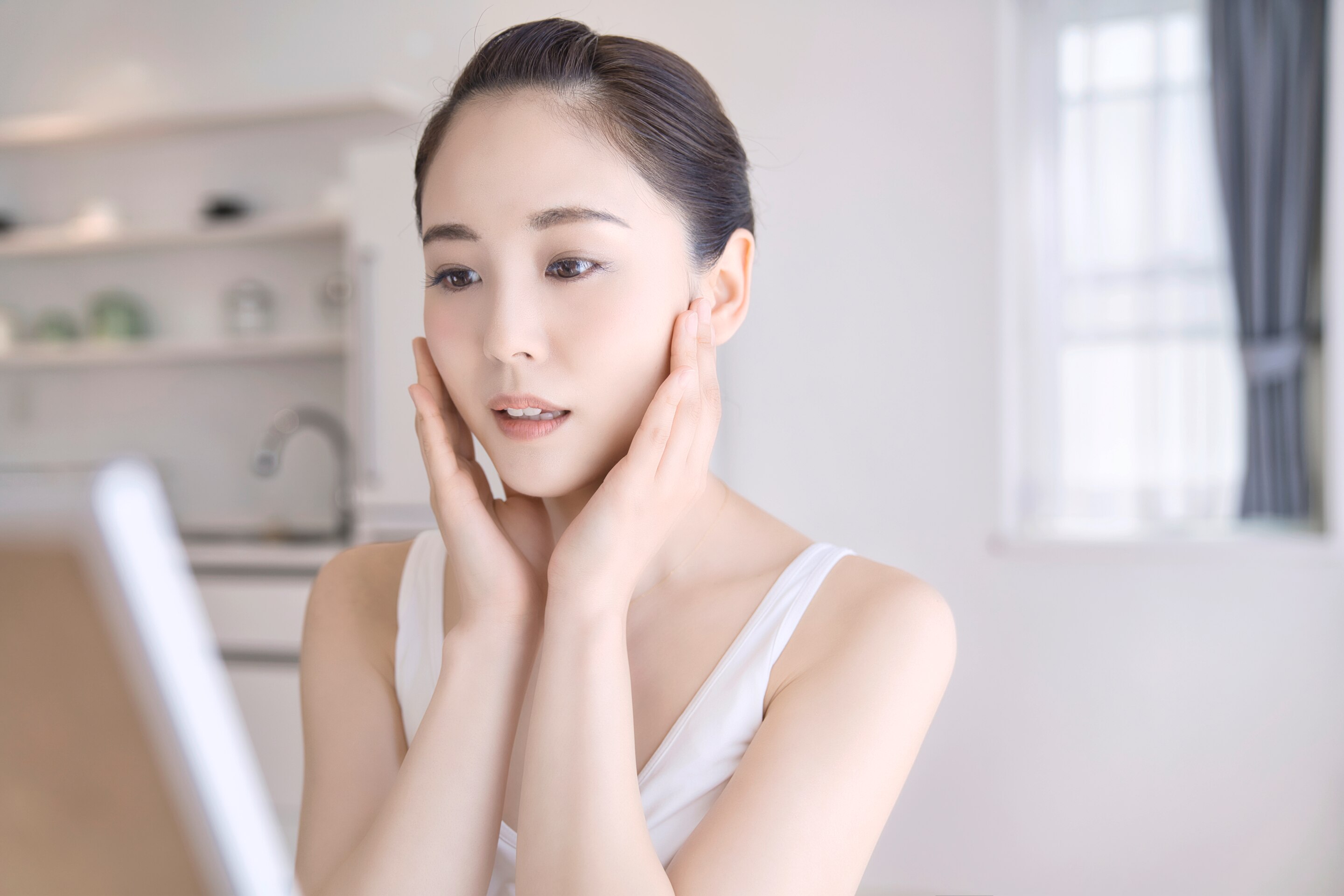 A woman touching her face while looking in the mirror