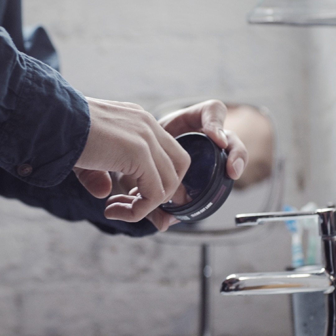 A guy scooping out some Axe pomade.