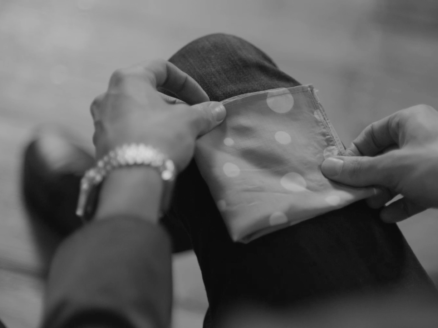 Un hombre con un blazer, ajustando su pañuelo de bolsillo.