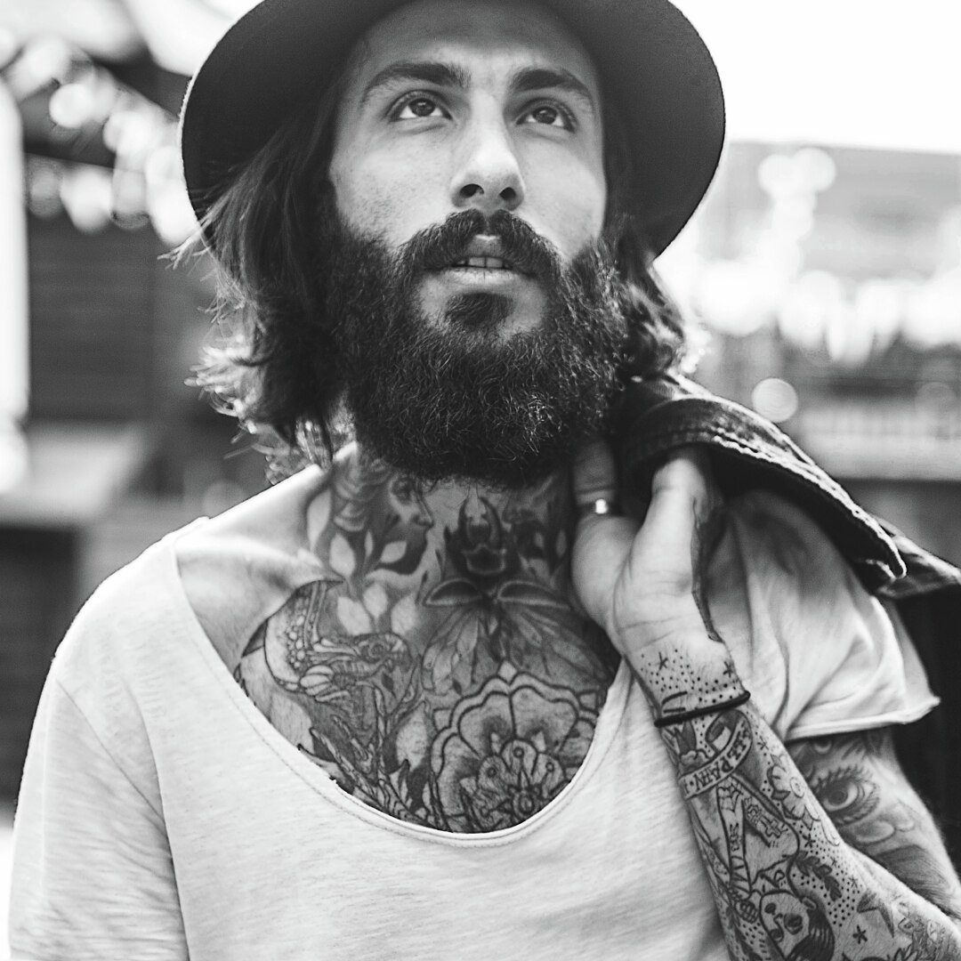 A guy with a full beard and tattoos.