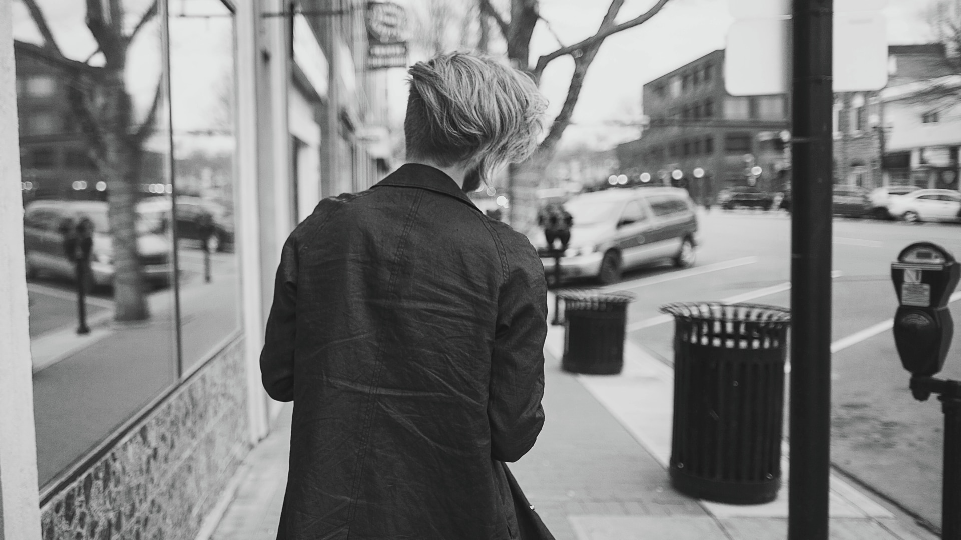 Un hombre de pelo largo, caminando por una calle de una ciudad.