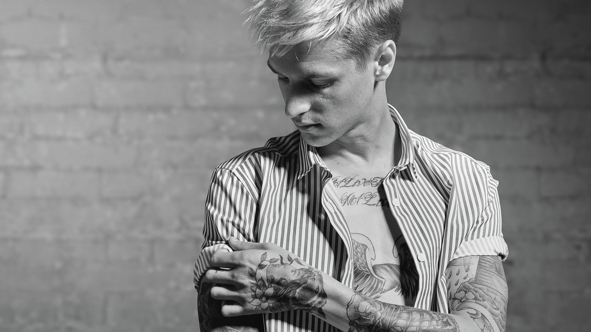 Un hombre con una camisa a rayas, mostrando sus tatuajes.
