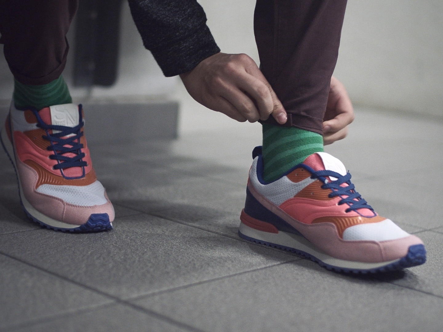 A guy in brightly colored trainers, with cuffed pants.