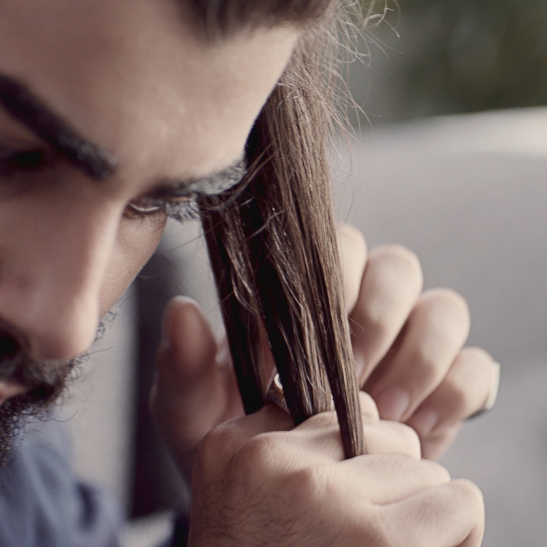 A guy separating his hair into strands to braid it.
