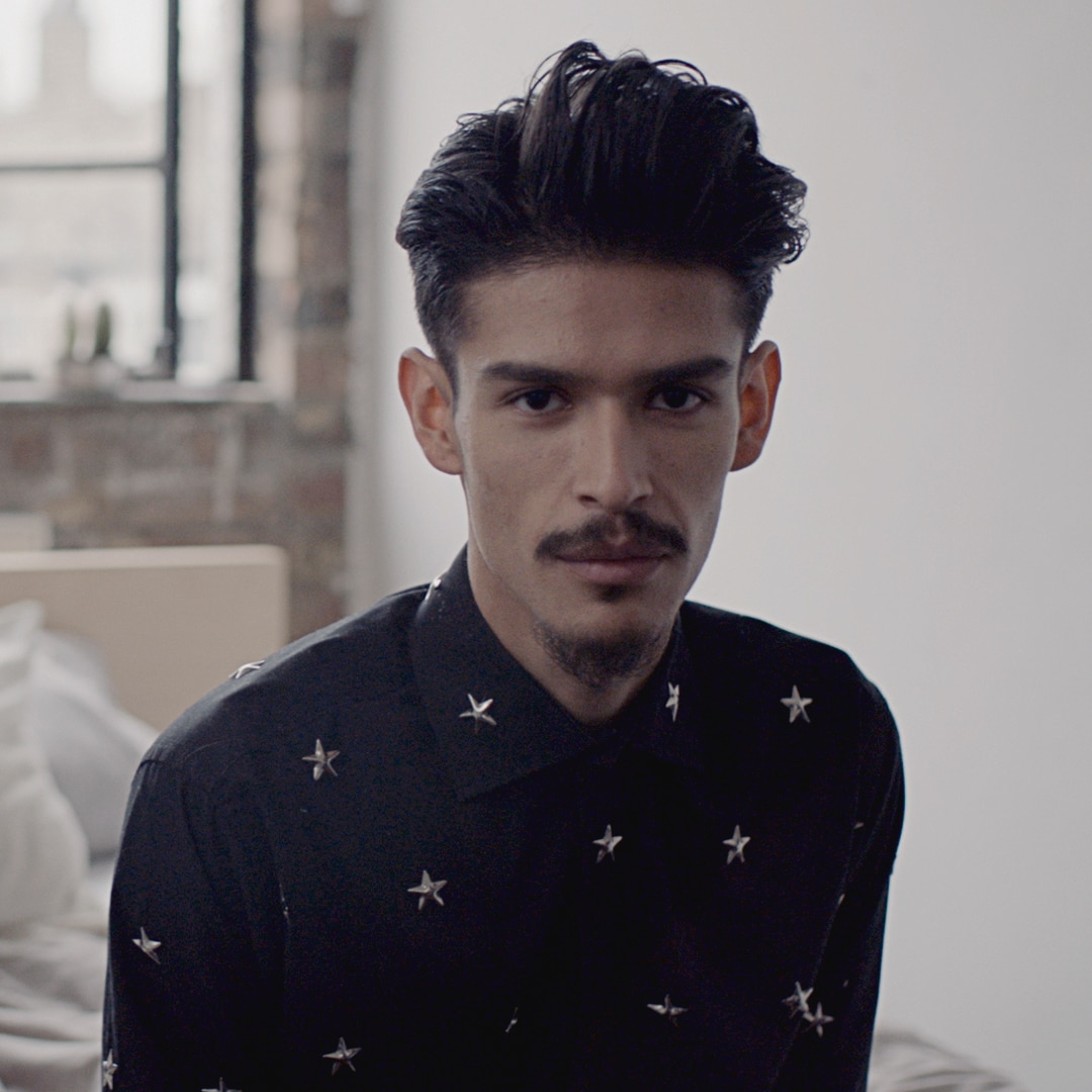 A guy with a moustache, quiff and star-studded shirt.