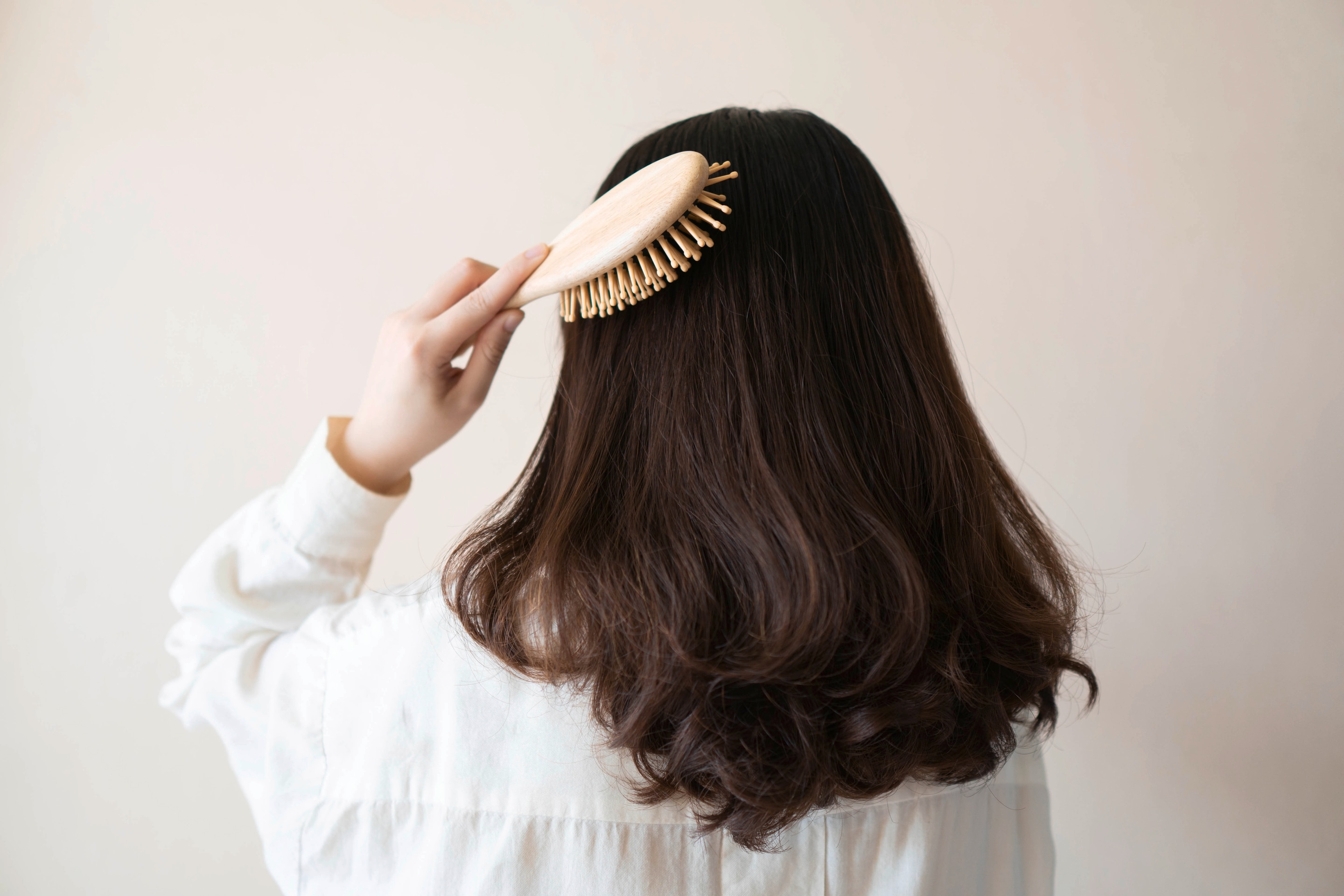 Back view of a woman in white brushing her hair