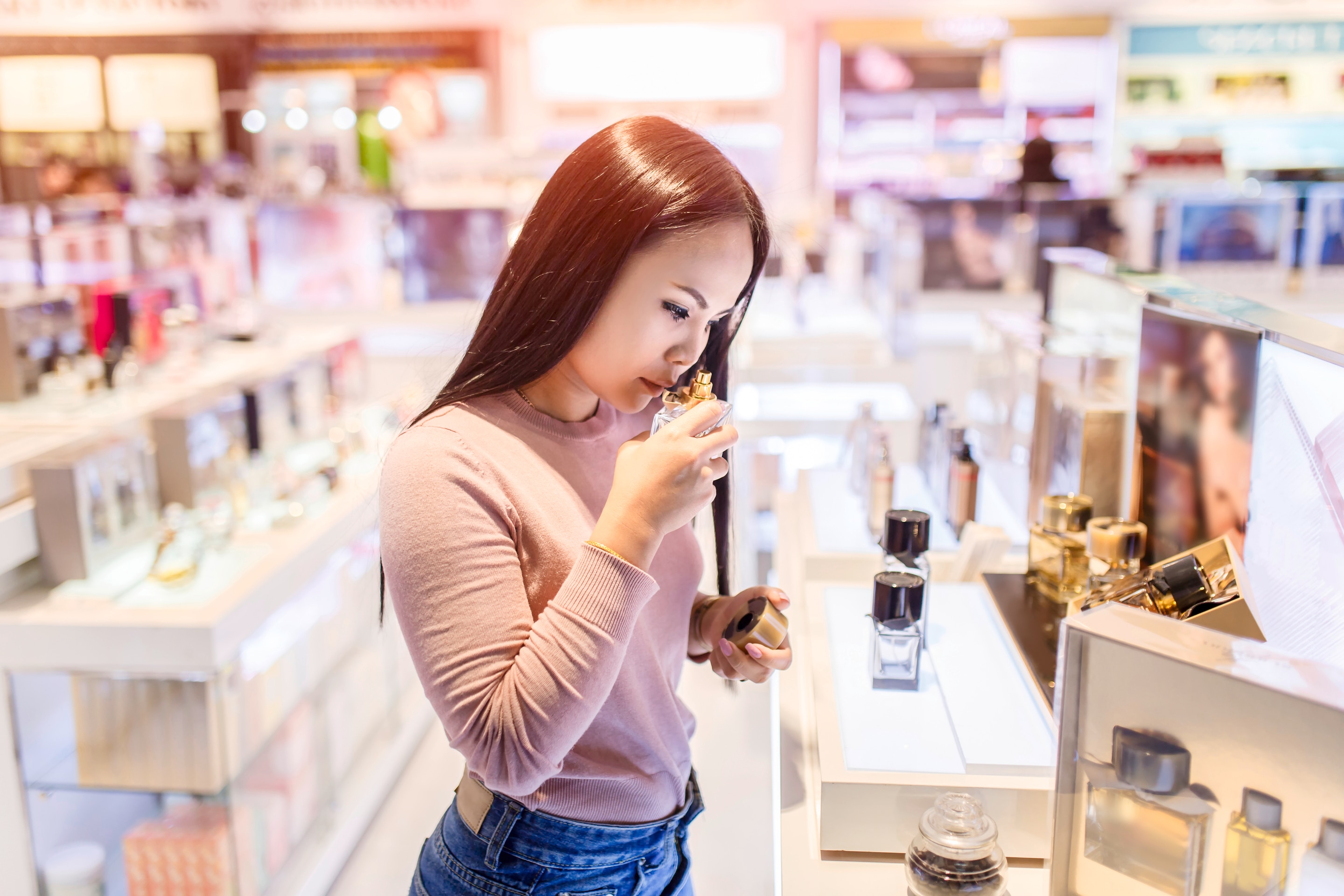 An Asian woman testing fragrances at the mall