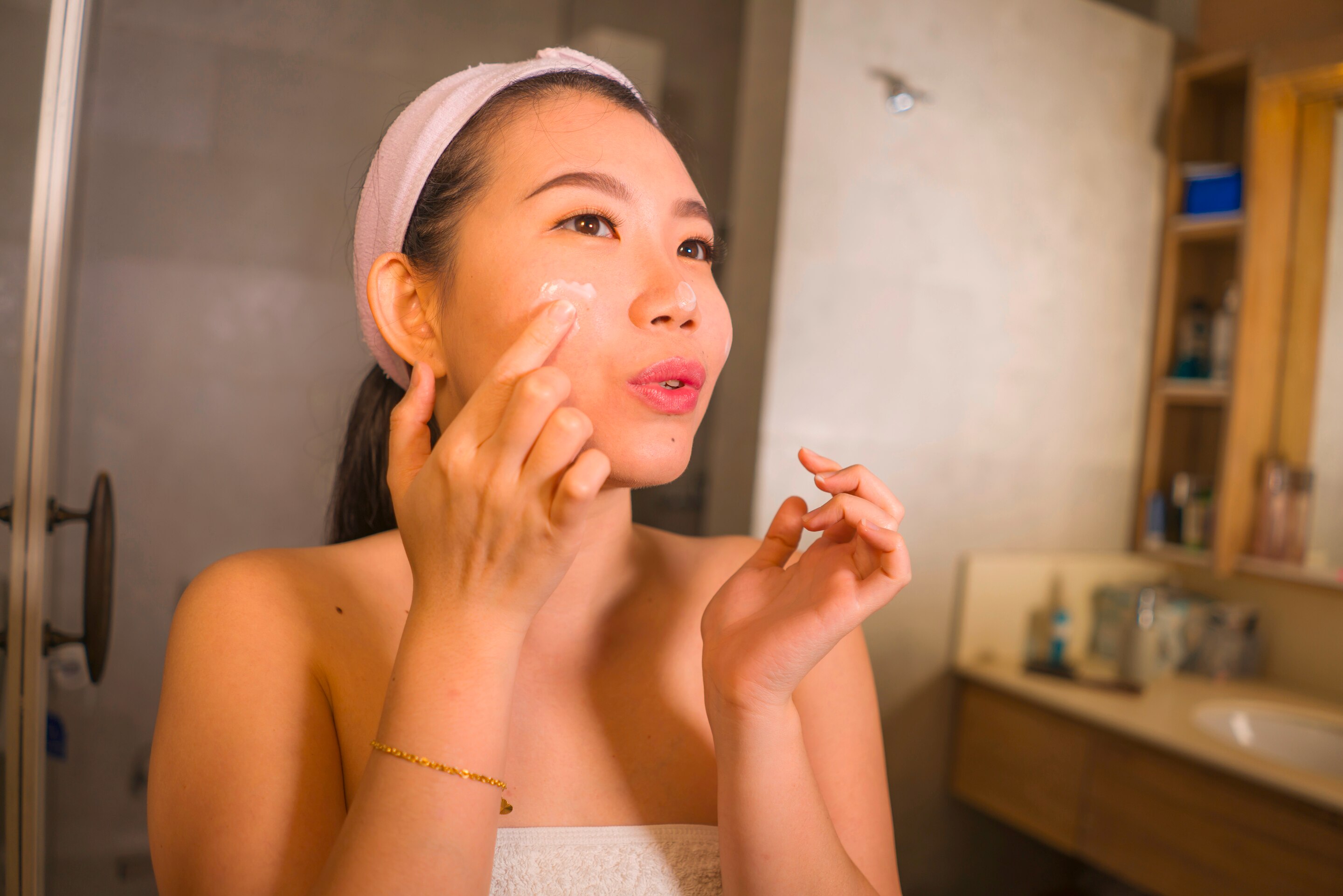  A woman applying face cream in the bathroom