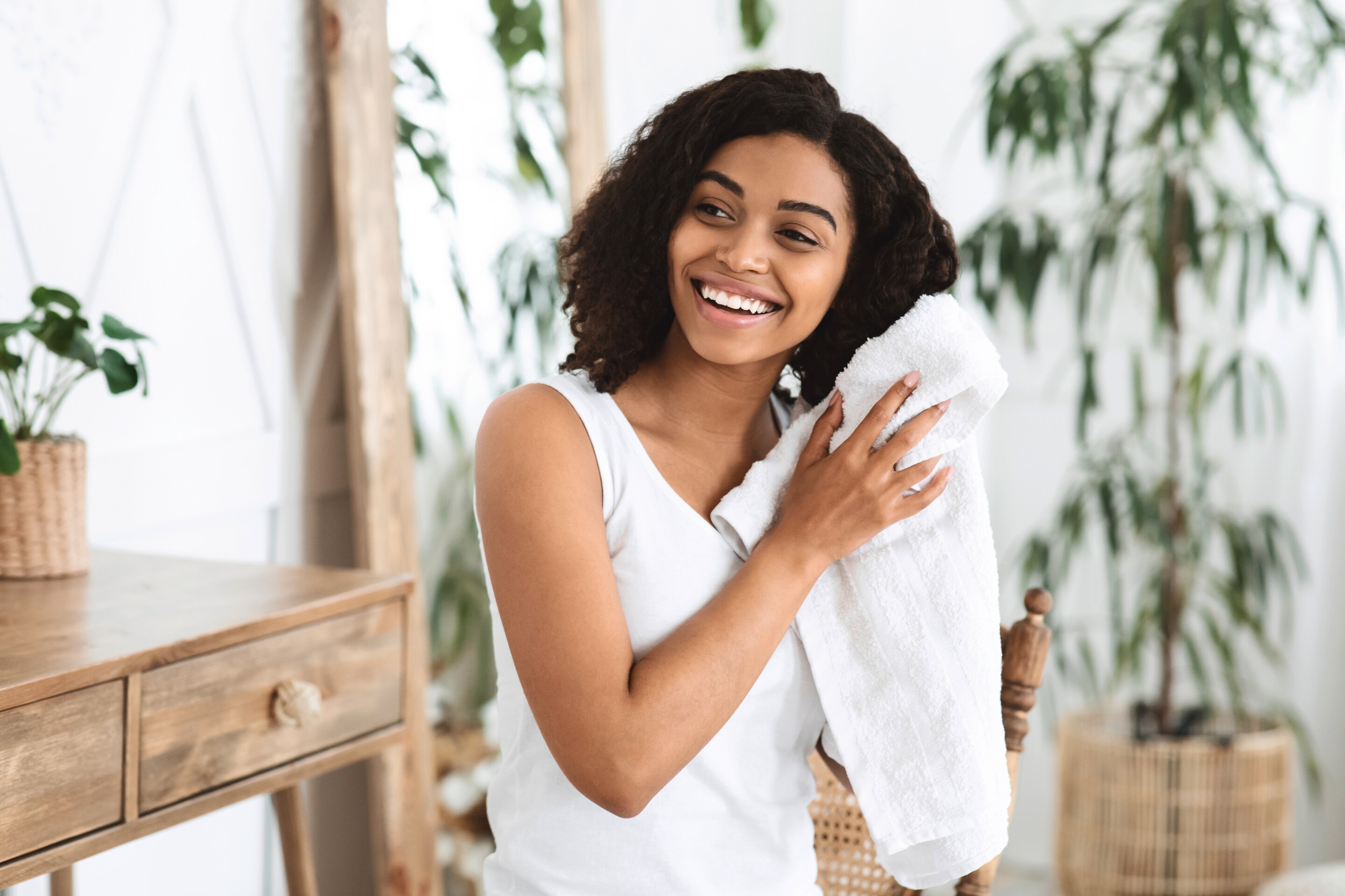 A smiling woman with curly hair drying her hair