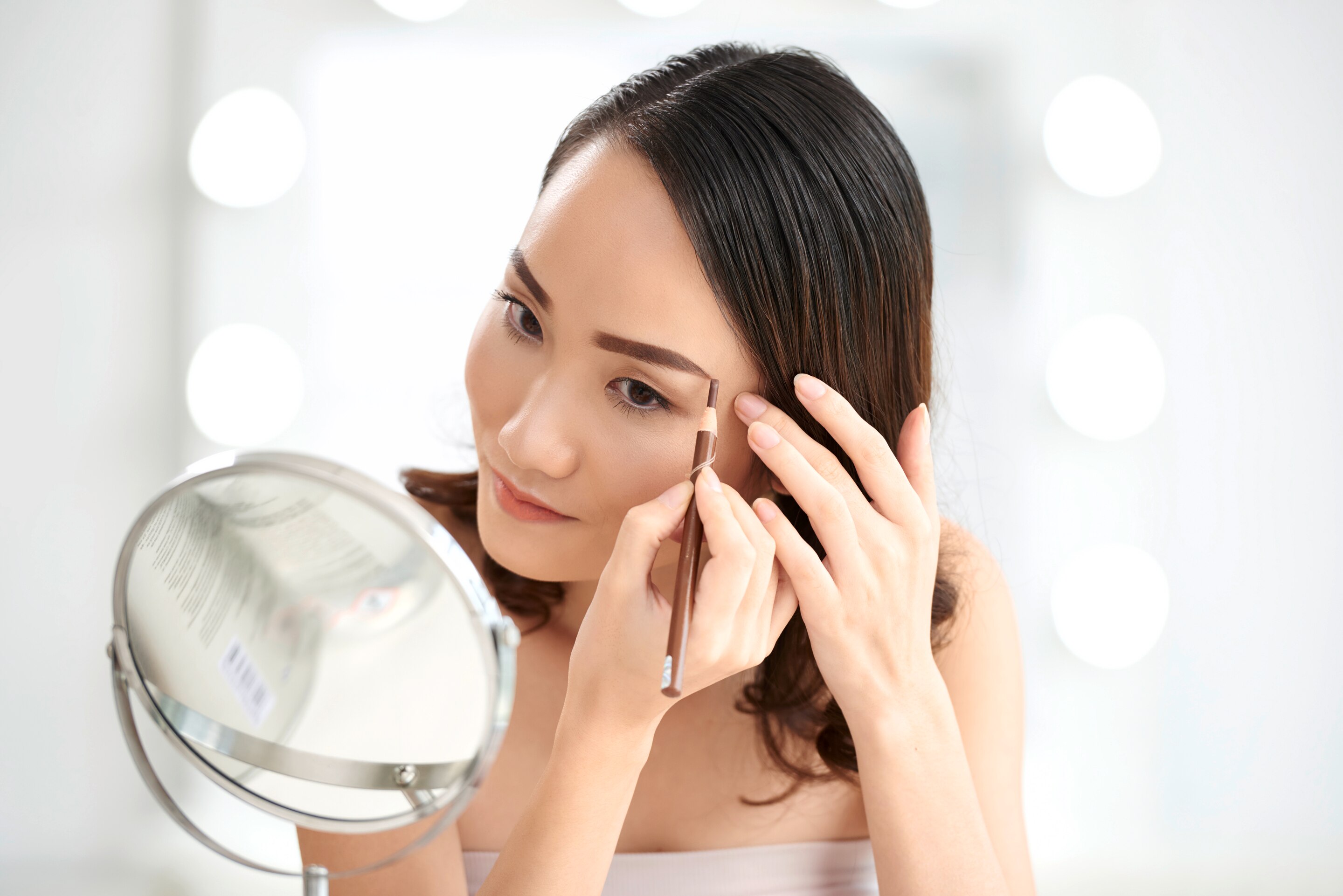 Asian woman shaping her eyebrows