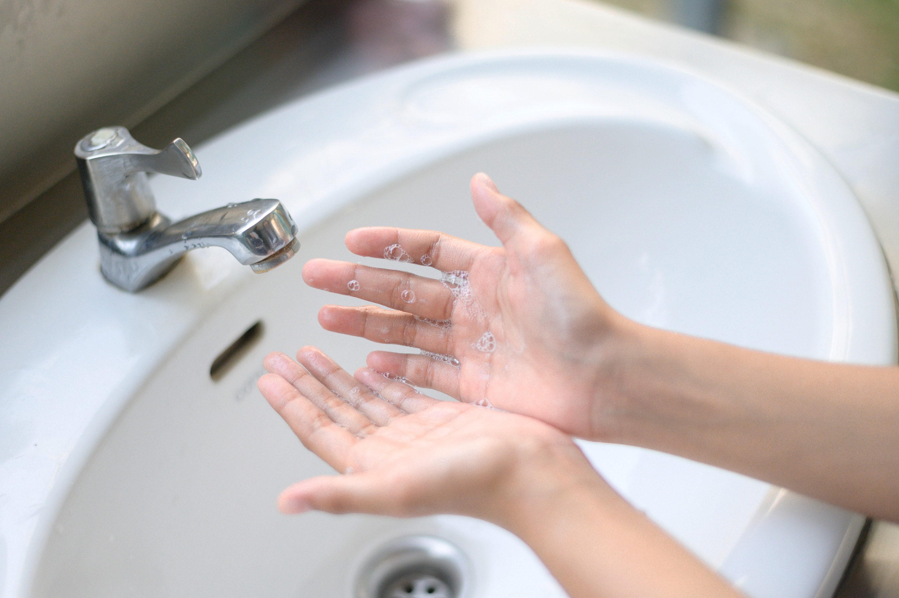 A pair of soapy hands under a faucet