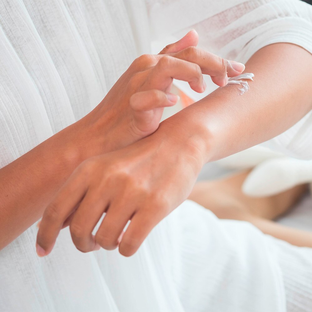 Woman applying body lotion to arm