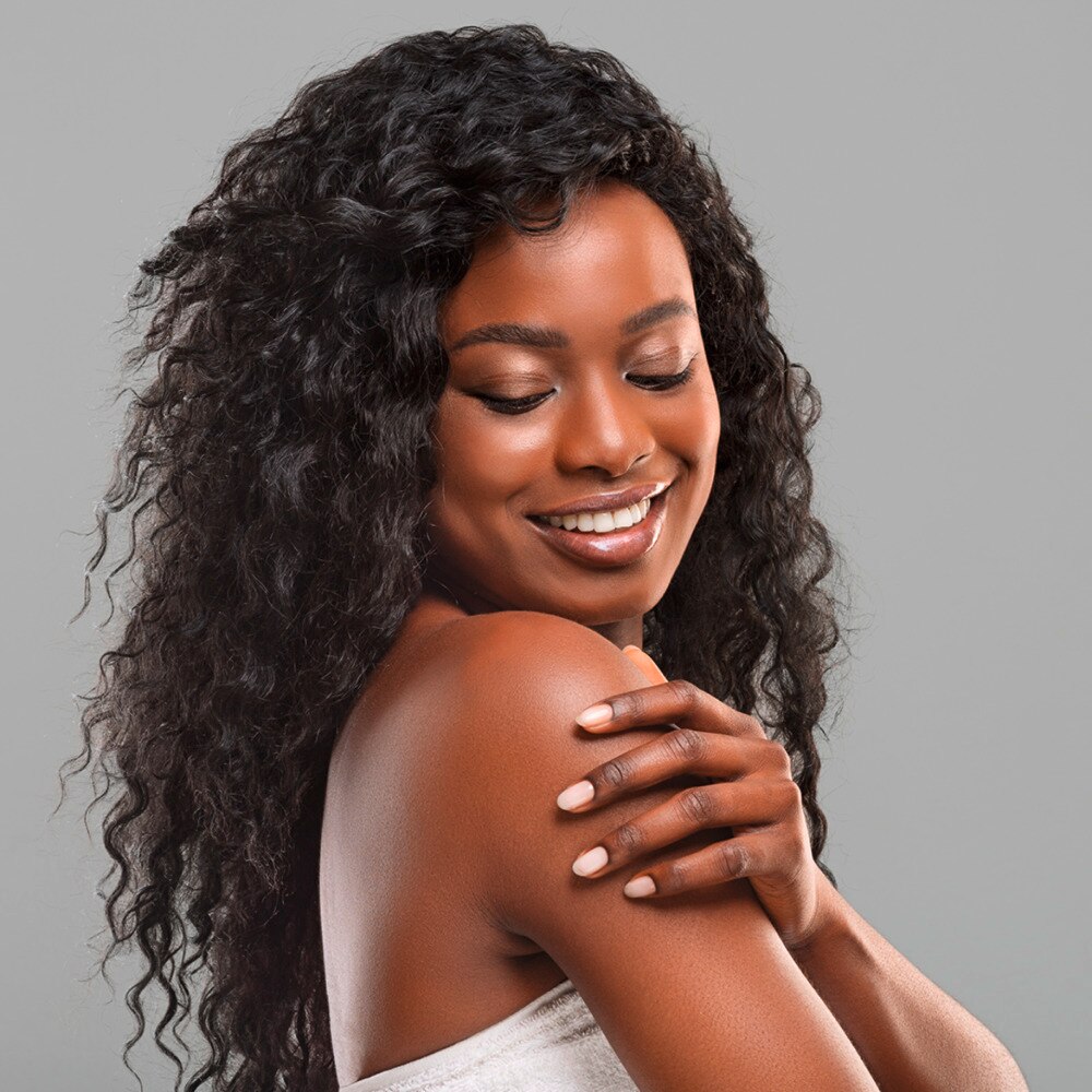 Beautiful dark skinned woman touching her skin on shoulder