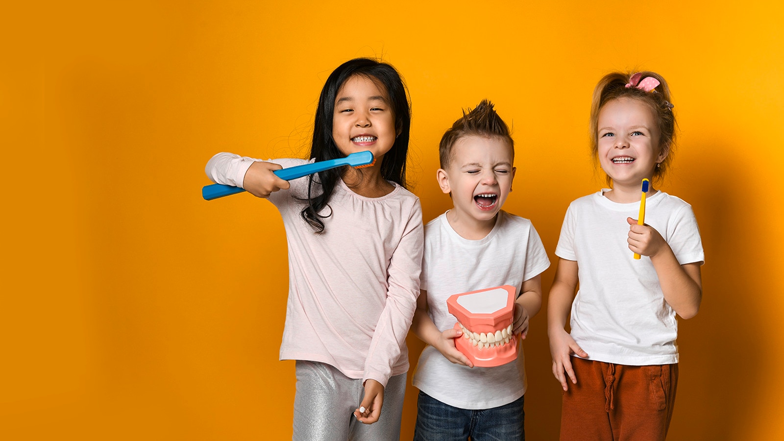 Young child in a red and white striped shirt brushing their teeth in front of a mirror