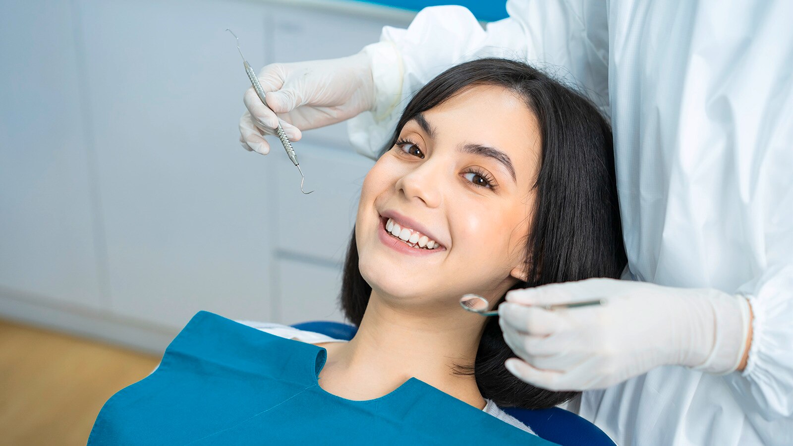 Closeup of a young woman in a white shirt checking her teeth and gum health in a mirror