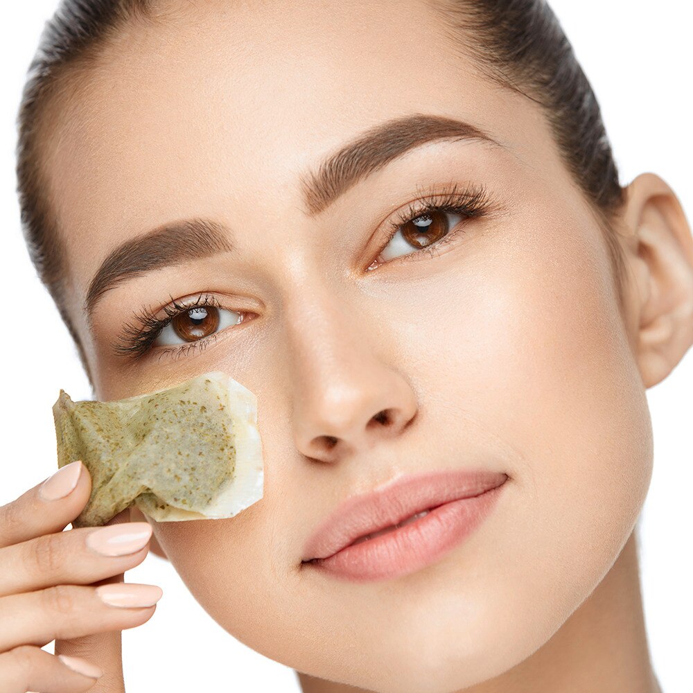 Woman with healthy skin applying tea bag under eye
