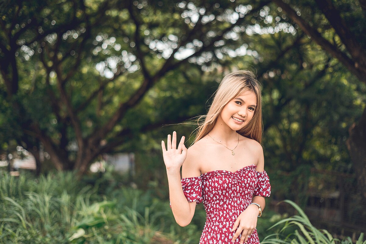 Asian woman with platinum hair and dark roots wearing red dress