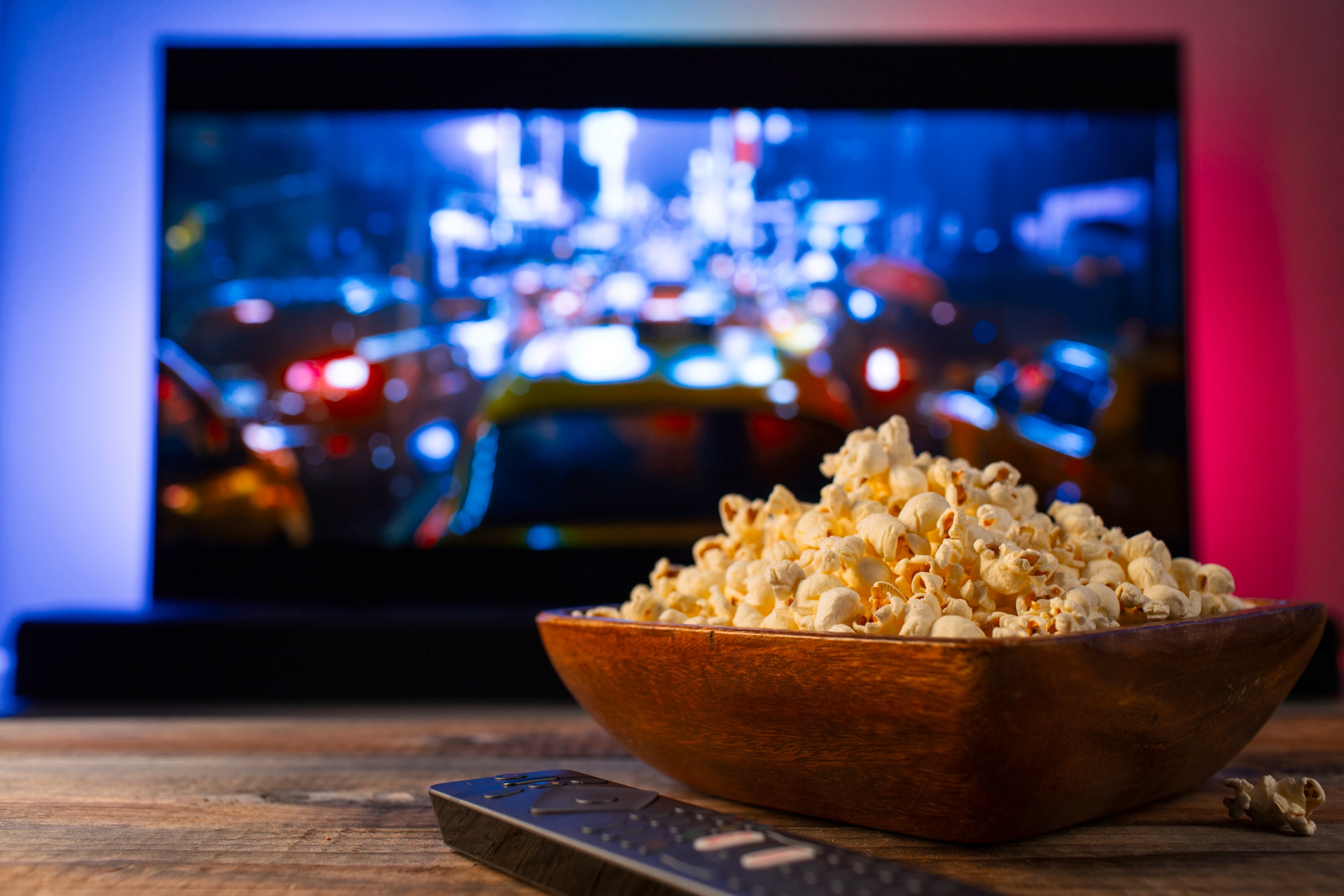 TV layar lebar di ruang tamu dengan popcorn di atas meja	