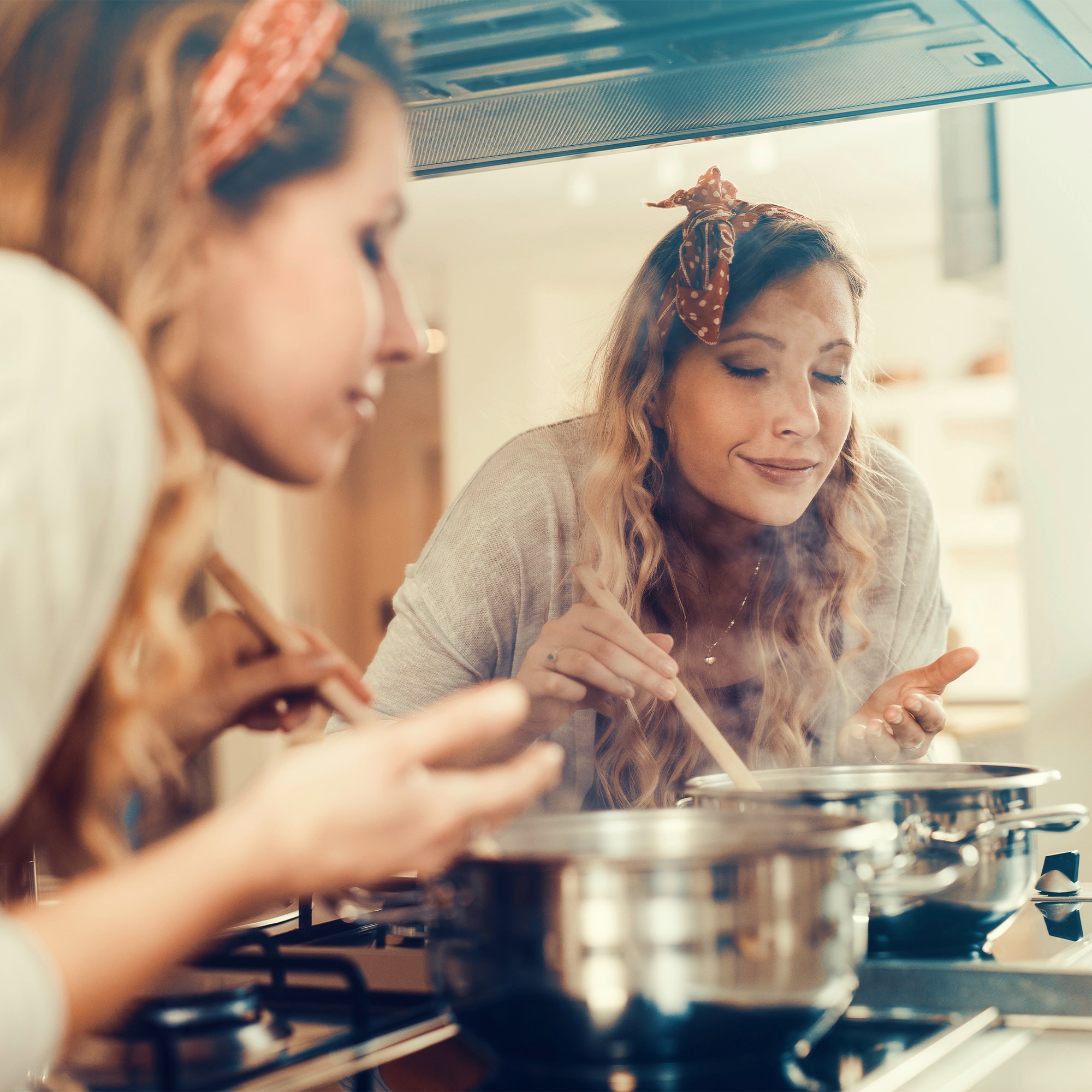 Women smelling delicious aromas from a pot.