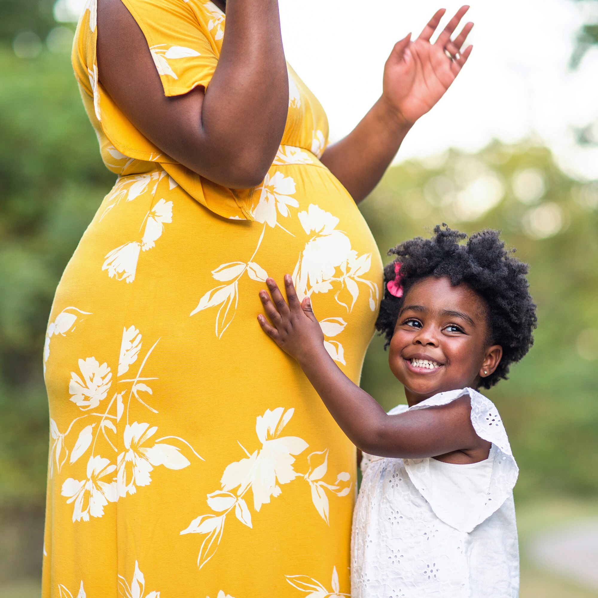 Little girl holding her pregnant mothers stomach