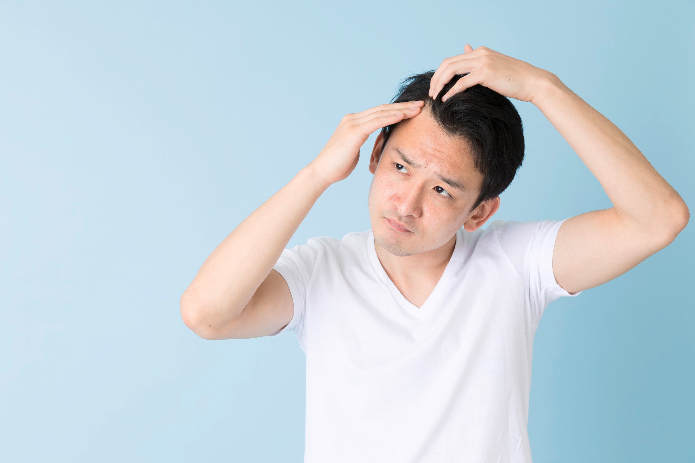 Young Asian man combing through his scalp with his fingers