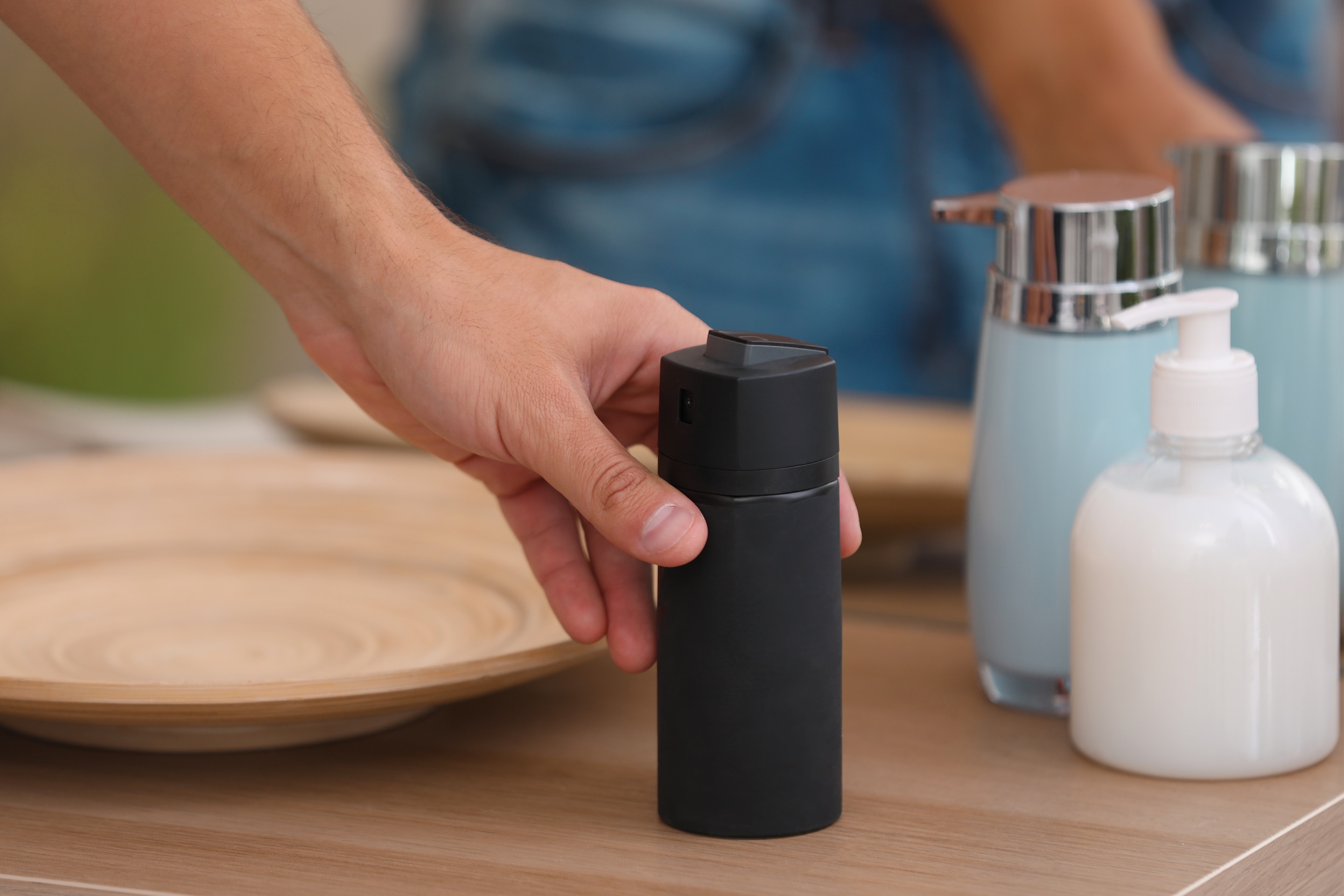 pria asia sedang mengambil botol deodorant di meja kamar mandi