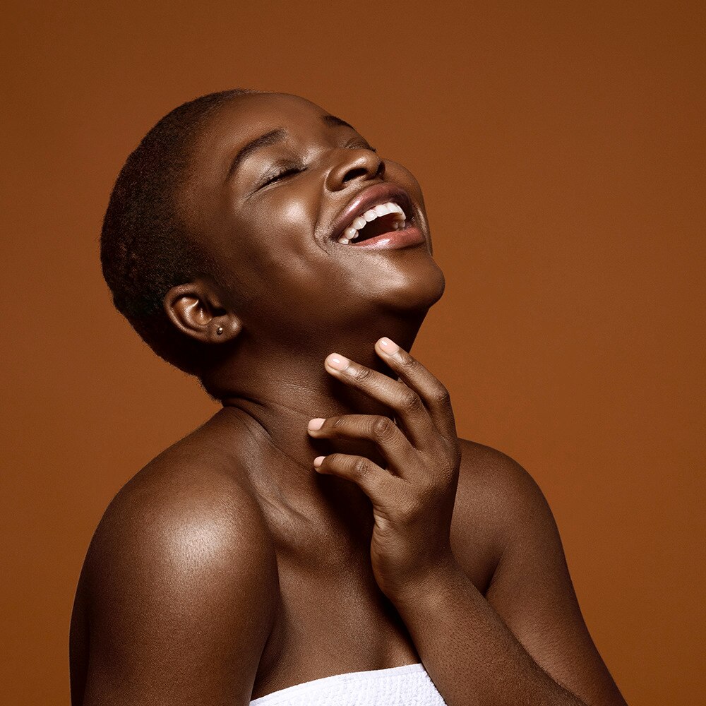 Black woman smiling with hand on her neck