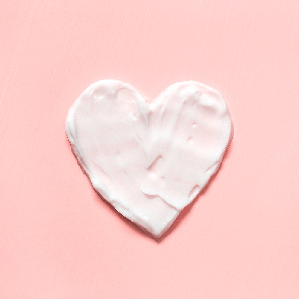 Heart made with Lotion on a pink background