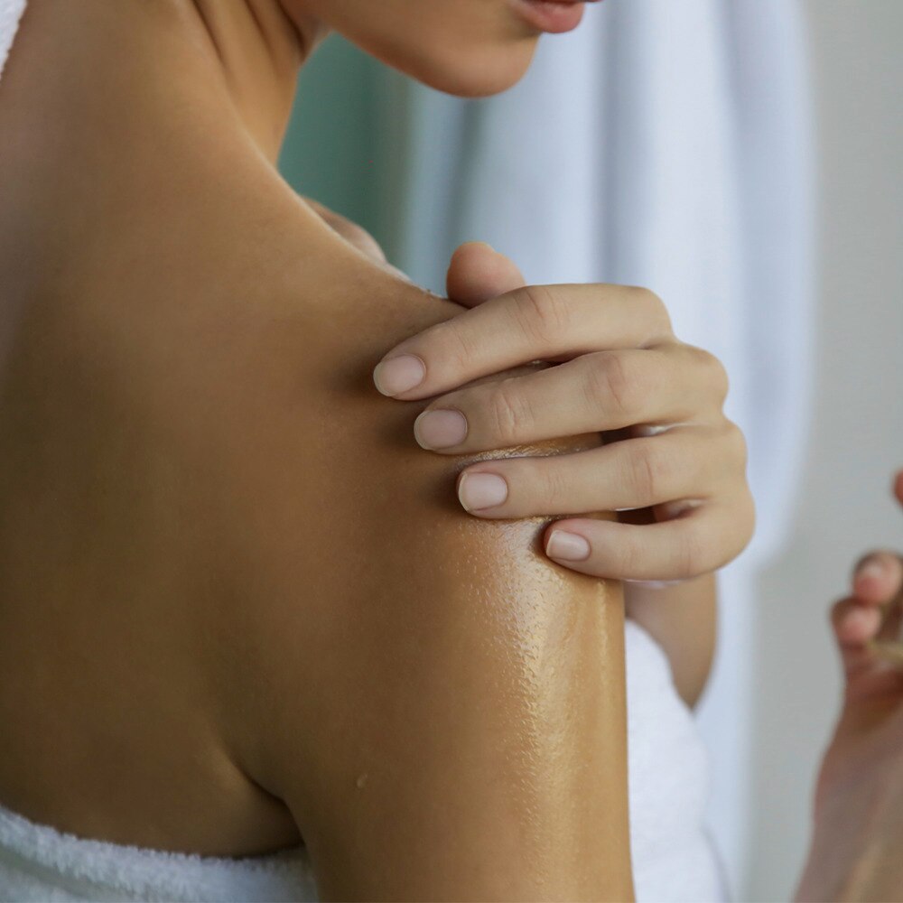 Lady applying oil on her sholder