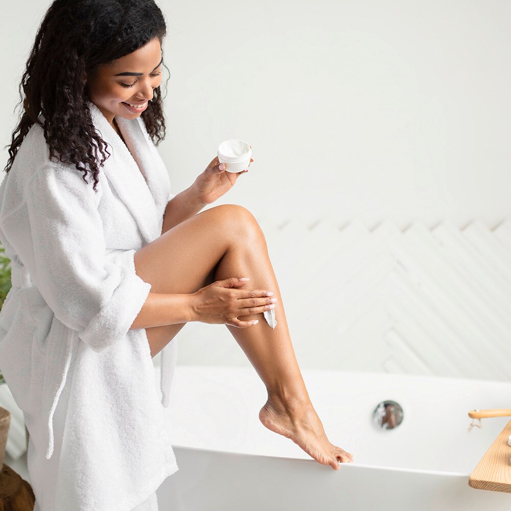 A girl applying creme on her leg