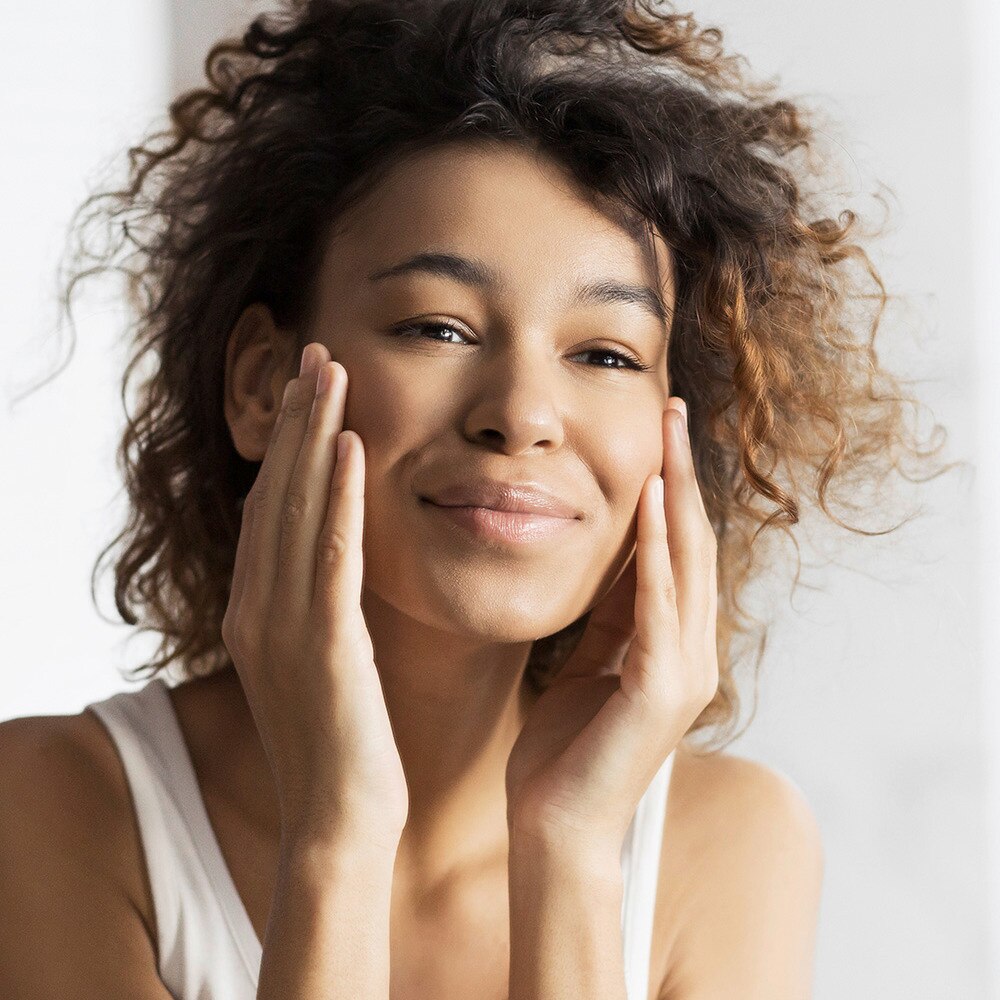 Happy lady with afro hair touching her face