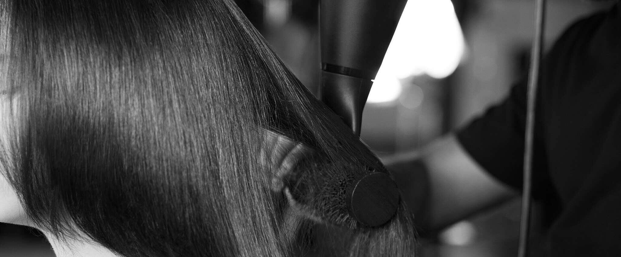 Primer plano del cabello fino de una modelo peinado con cepillo y secador.