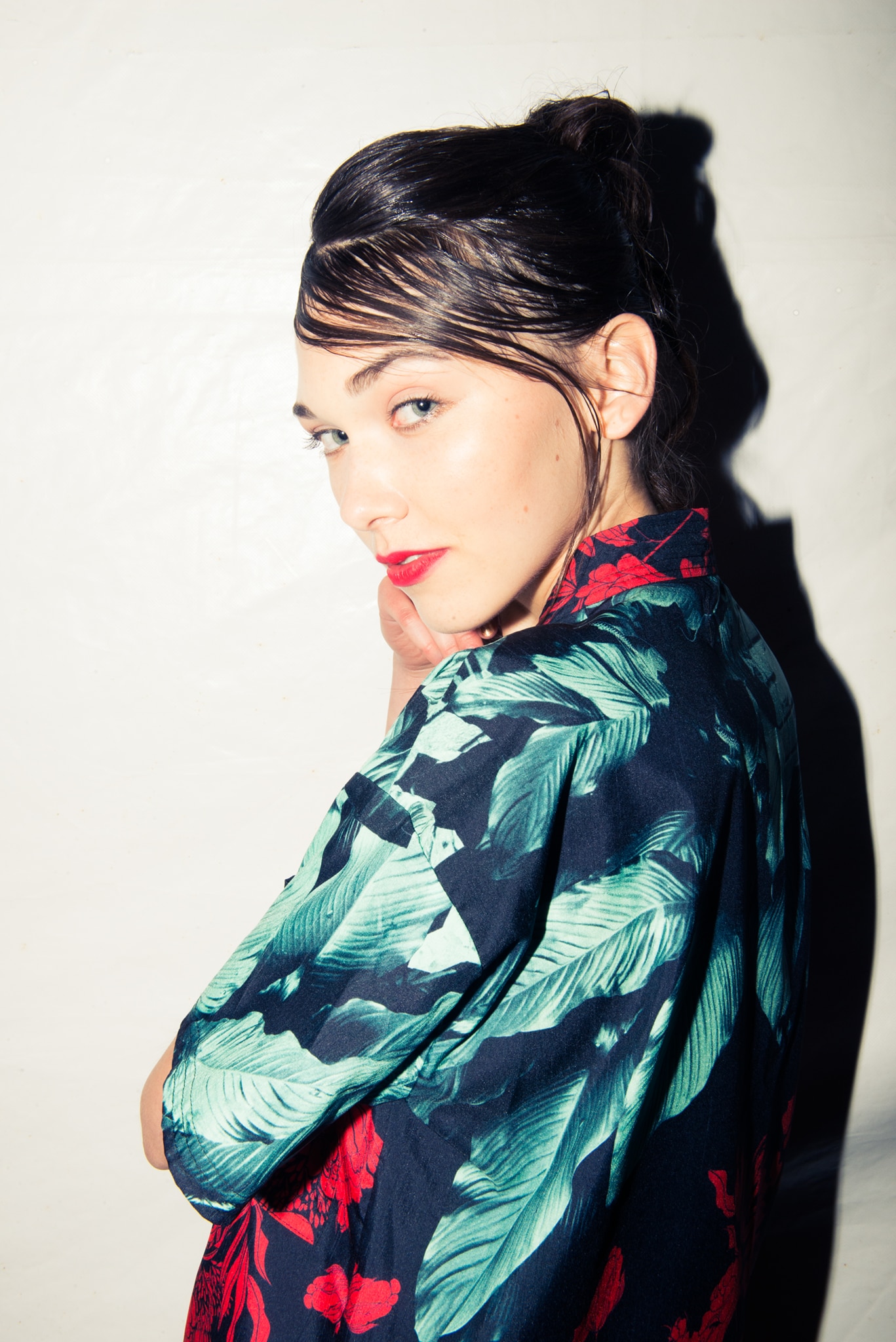 A model wearing a black, red and green floral blouse with wet look fringe  