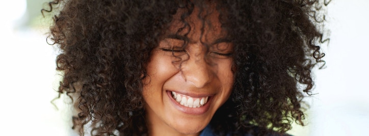 Woman with curly brown hair poses for photo to the page of tips and products for Curly Hair, Silk.