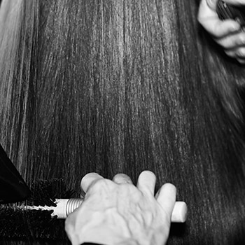 Close up of heat tongs being applied to a section of long dark hair.