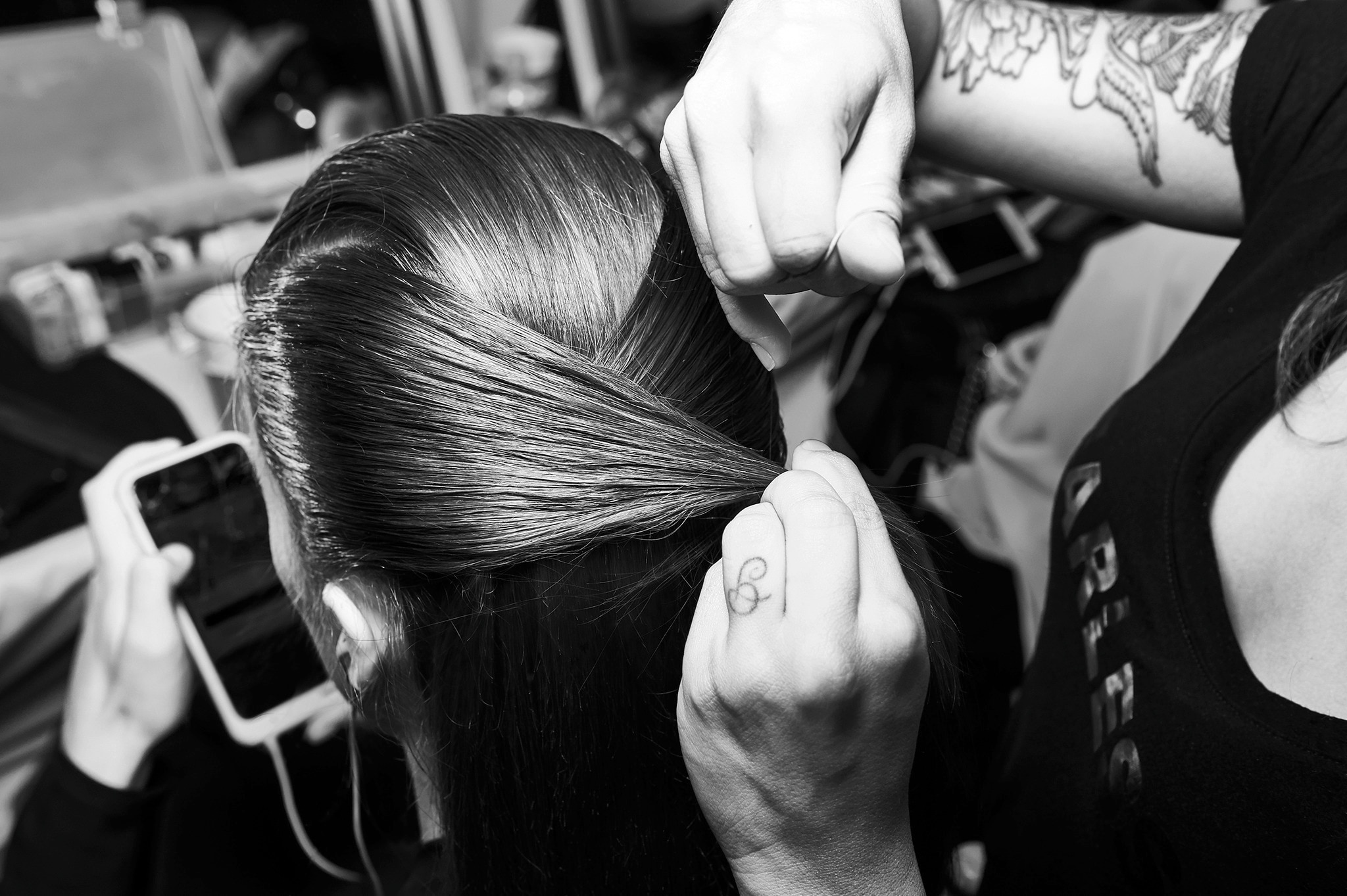  Egy stylist, aki egy a modell hajának két részét összefogja a modell feje mögött.