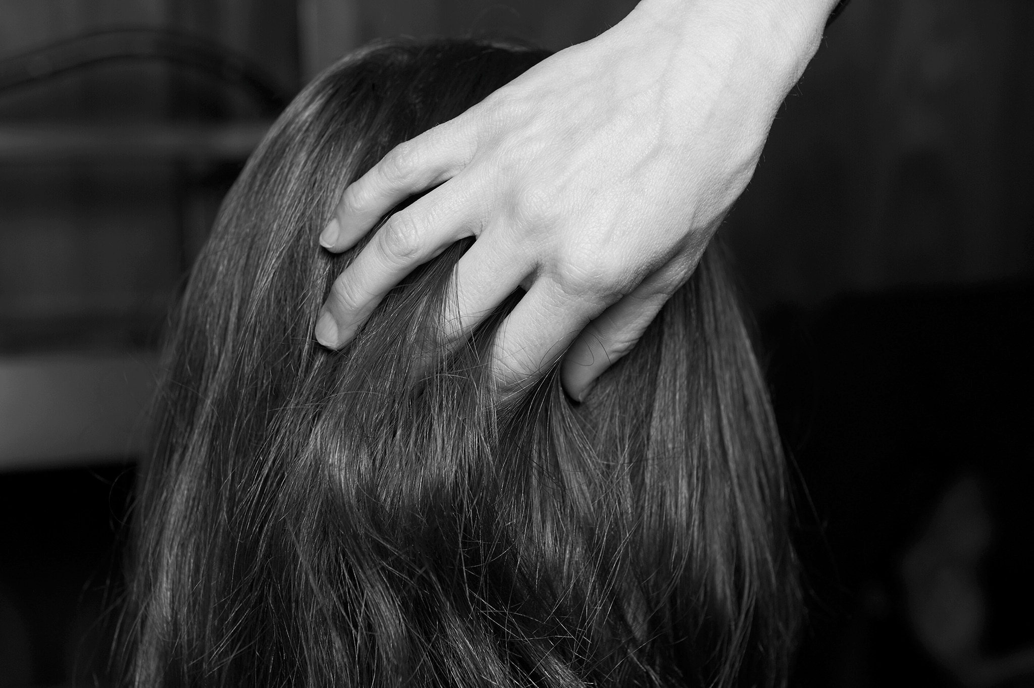 A close up of the back of a model's head with a stylist's hand running through it