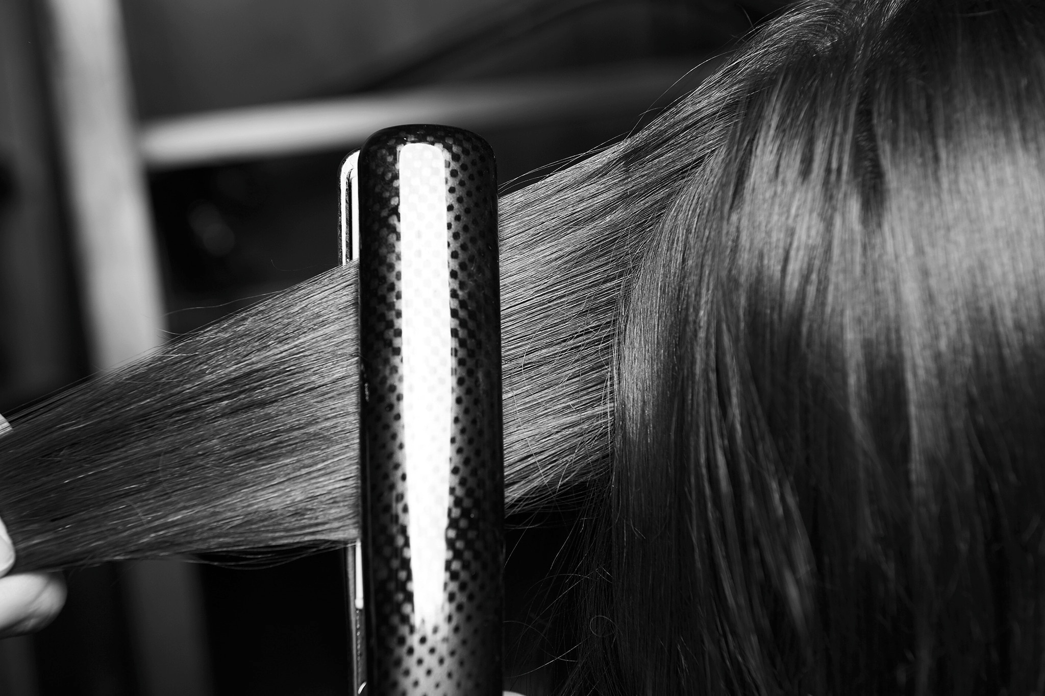 A stylist using curling tongs on a model's long