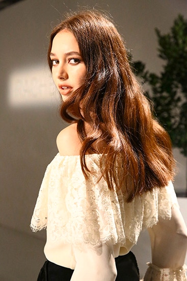 Una modelo luce una blusa blanca de estilo bohemio sin hombros y una falda negra