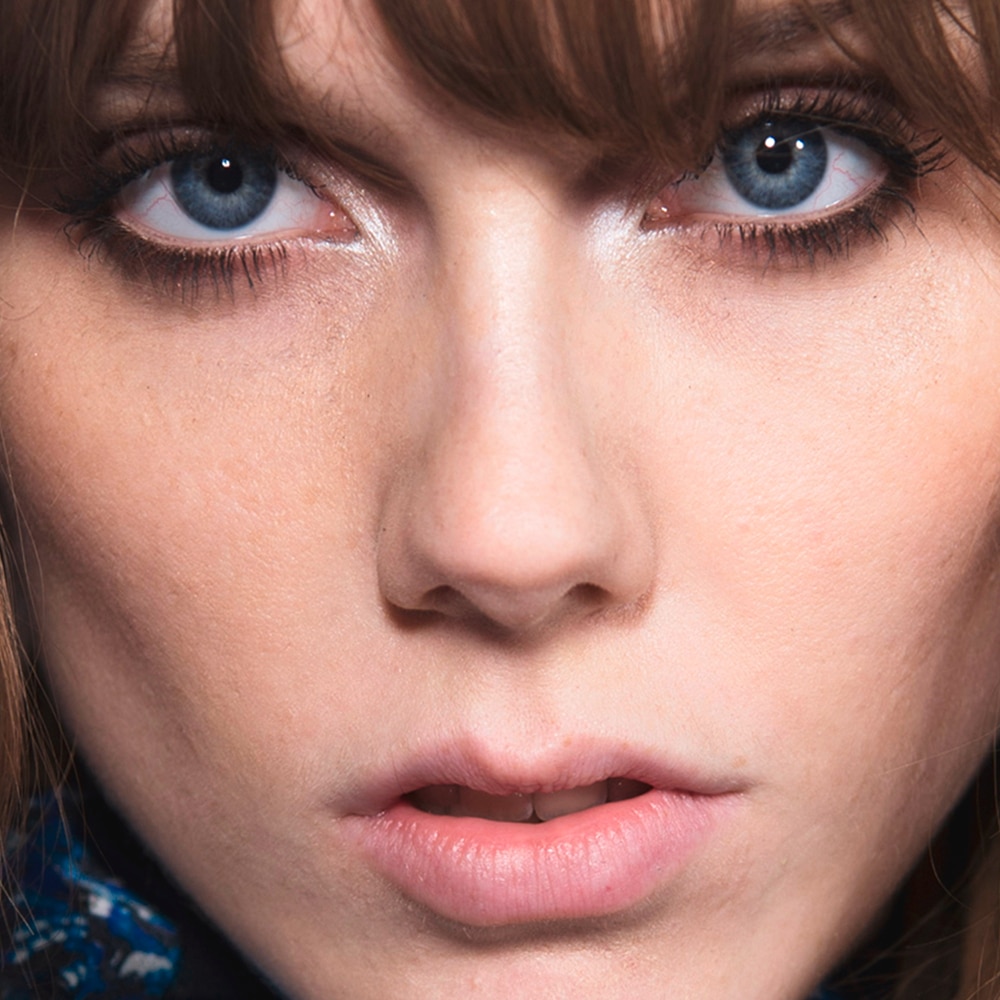 A model staring intensely at the camera with eyebrow length brown bangs 