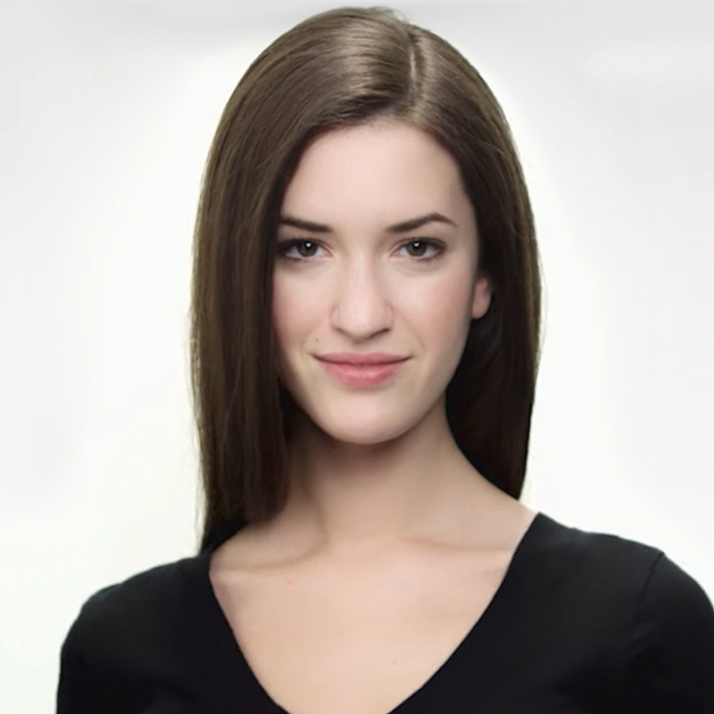 A smiling model with long brown hair in a parting, wearing a black V-neck top 