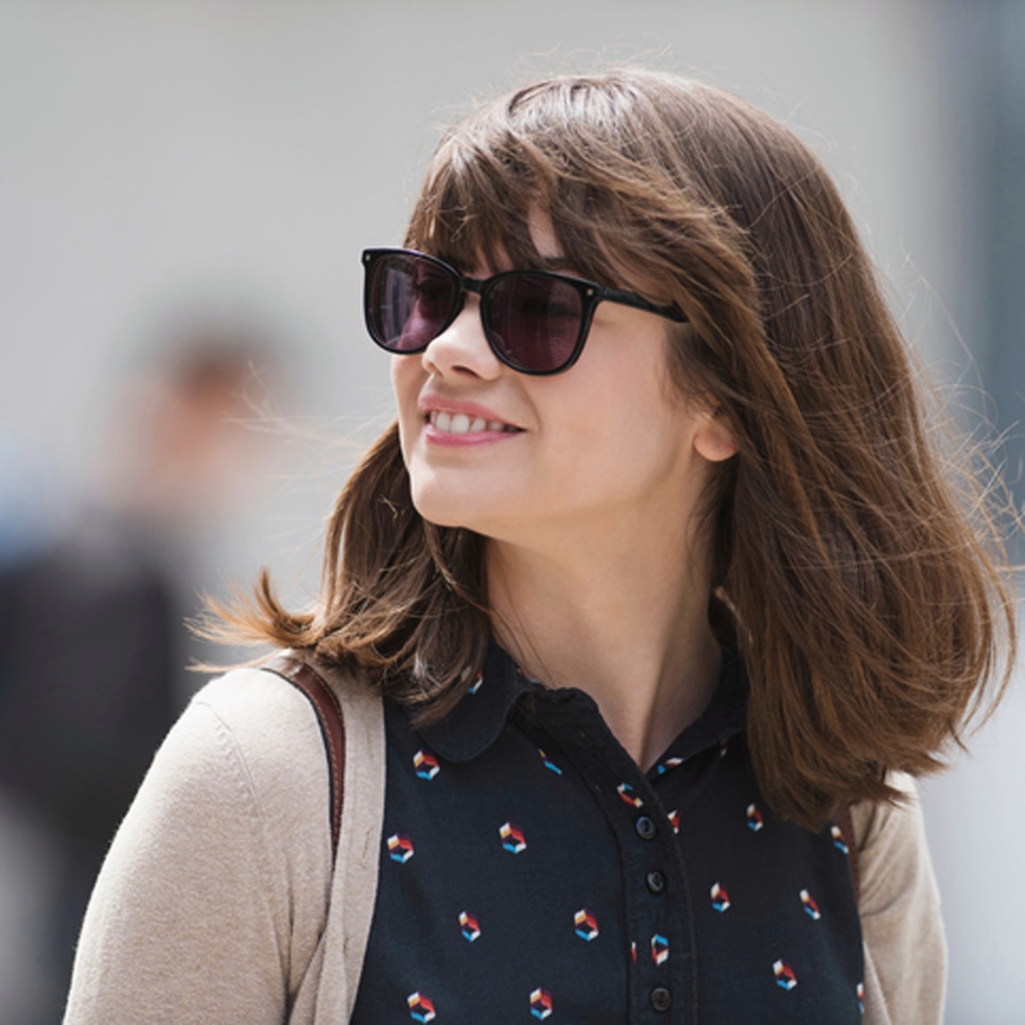 A woman with smooth hair, smiling and wearing sunglasses.