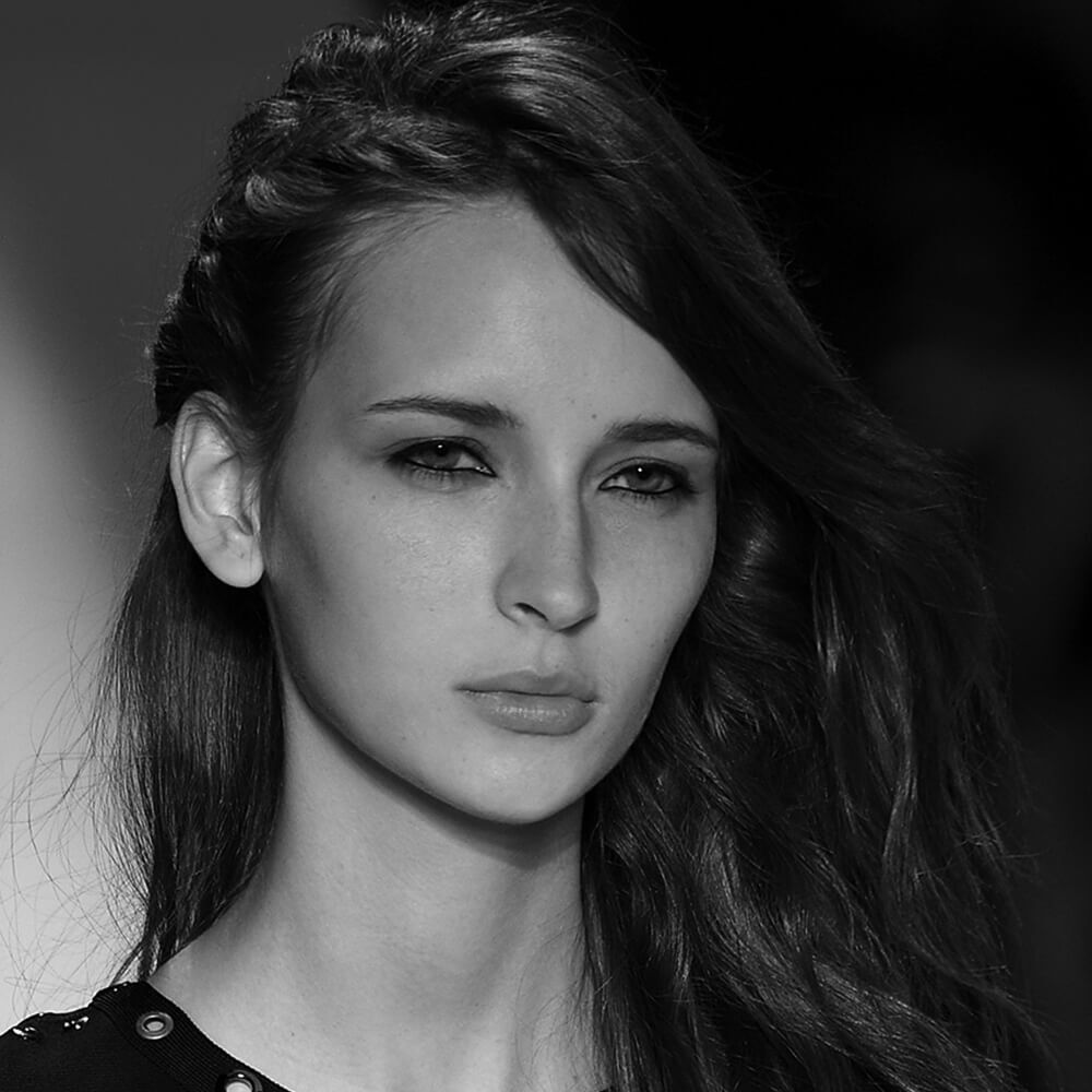 A model on the runway with her hair up in a messy braid on the right side of her head
