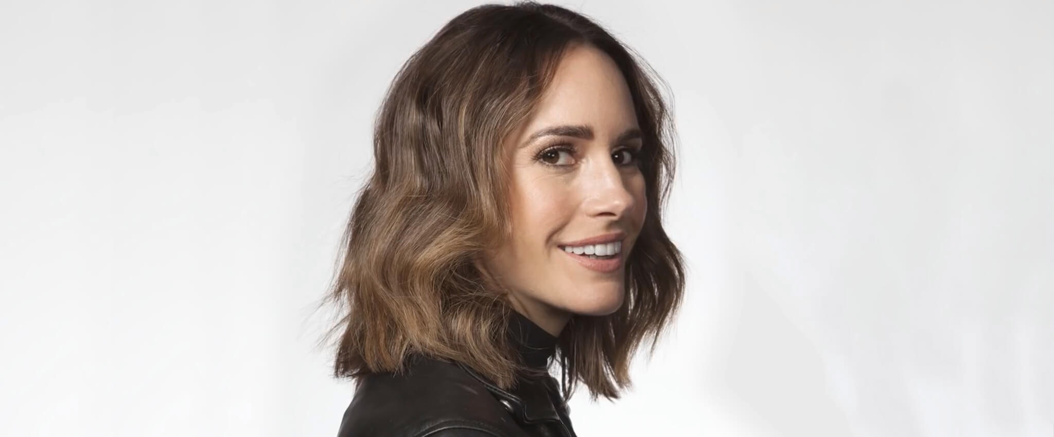 Louise Roe smiling at the camera, wearing a black leather biker jacket