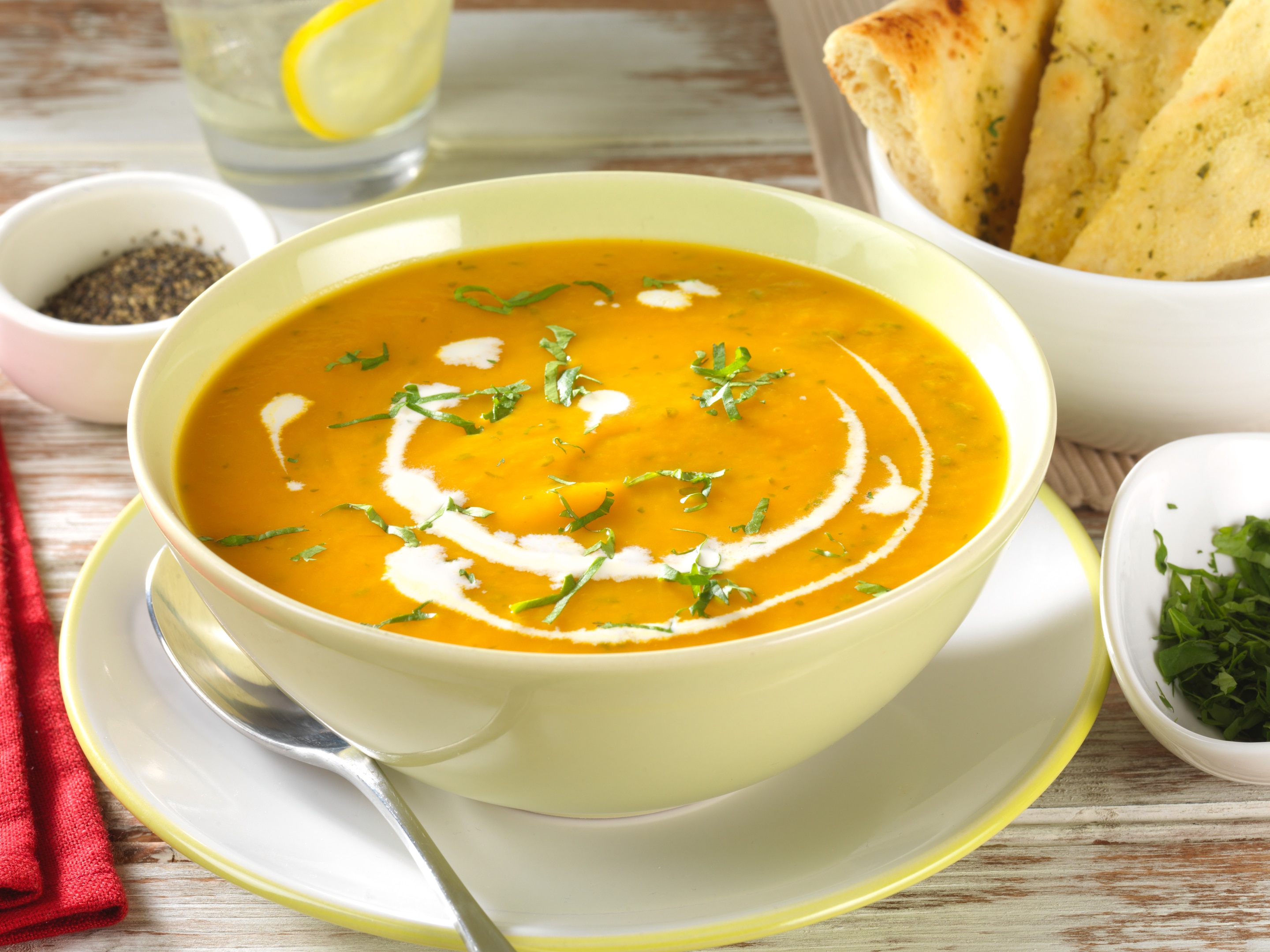 carrot and corriandersoup in a bowl with spoon and naan bread in a bowl