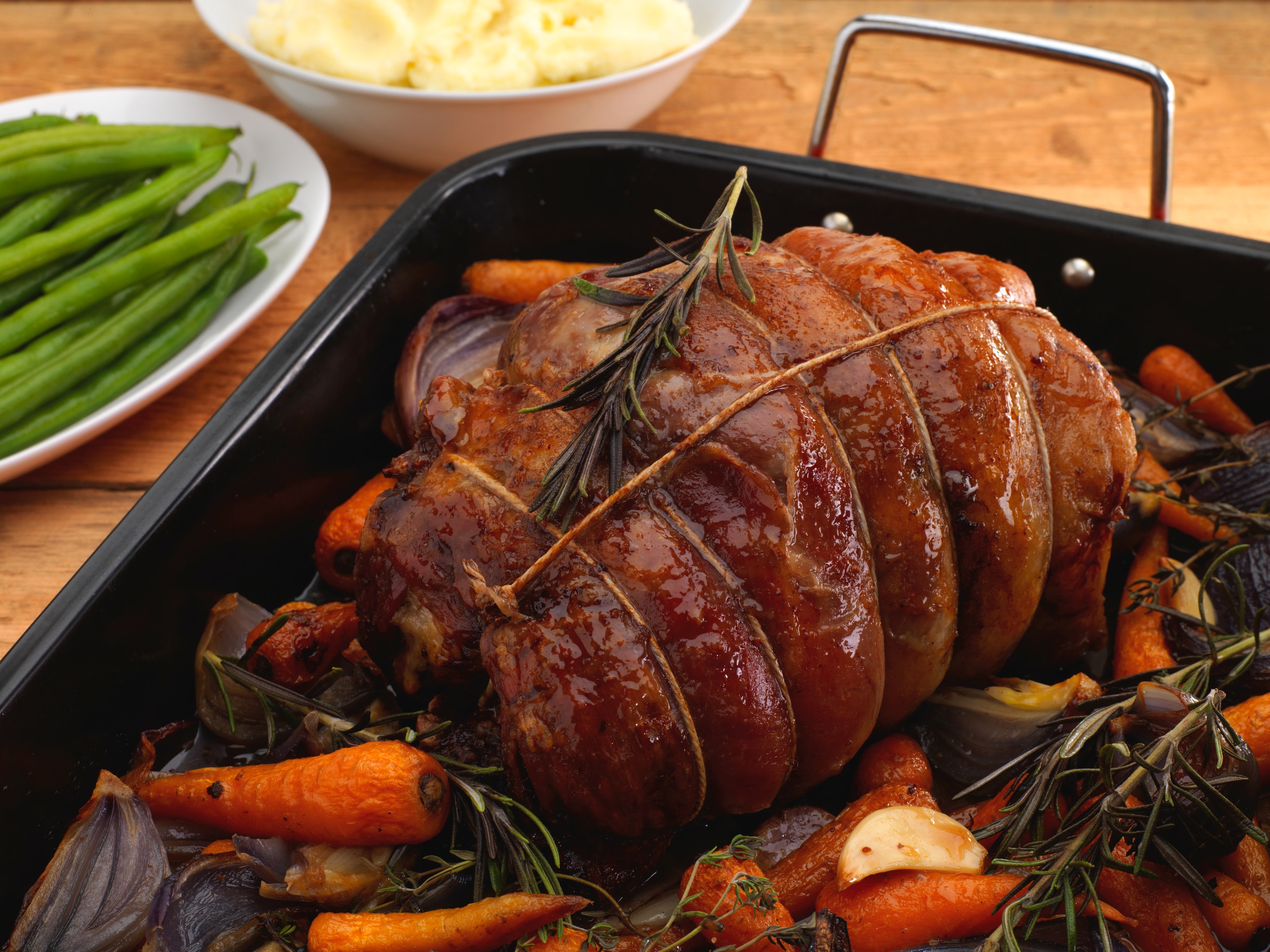 Roast shoulder of lamb in tray with roasted vegetables