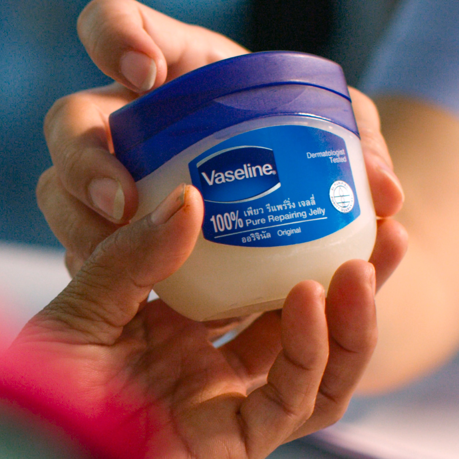 Vaseline Healing Jelly jar being passed on from one hand to another