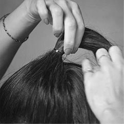 The back of a female model's head. Her long brown hair is gathered into a large chic bow.